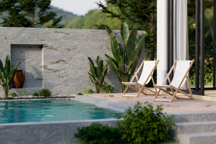 Two white lawn chairs sit by a pool. The pool is surrounded by large plants.